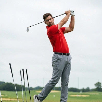 Golfer practicing swing on a driving range, focused and determined, with golf clubs in the background
