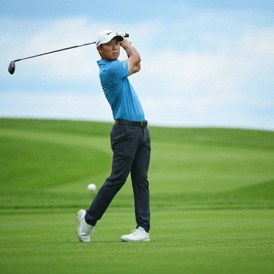 Professional golfer in mid-swing on a green course, action shot, no text, no words, no typography, no labels, clean image