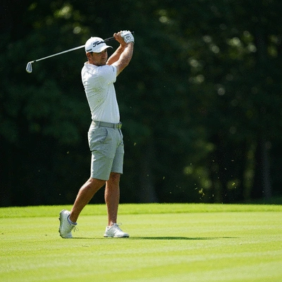 Professional golfer mid-swing on a green course