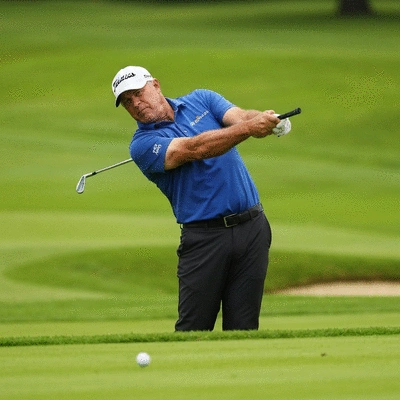 Professional golfer at the precise moment of impact, clubface meeting ball, dynamic action shot, green golf course background